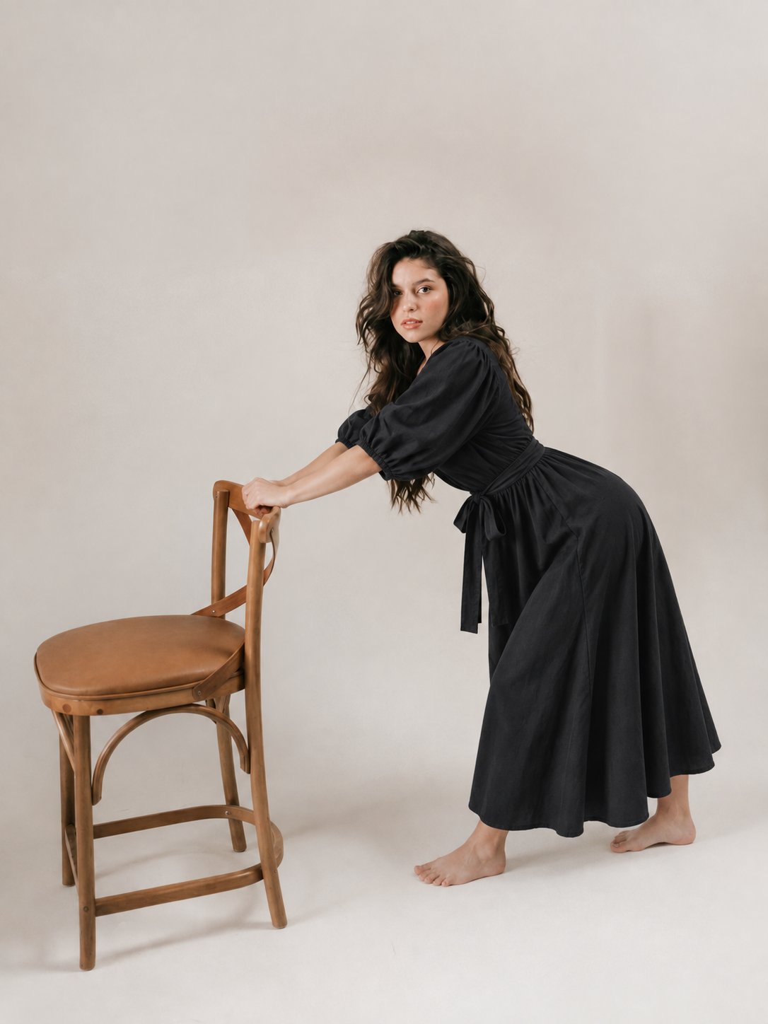 robe bubblee noir ete brune femme debout pose élégante avec robe longue en coton avec chaise décor
